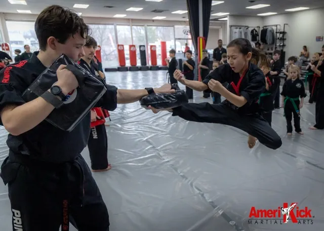 Amerikick Princeton student landing a flying side kick on a partner's pad