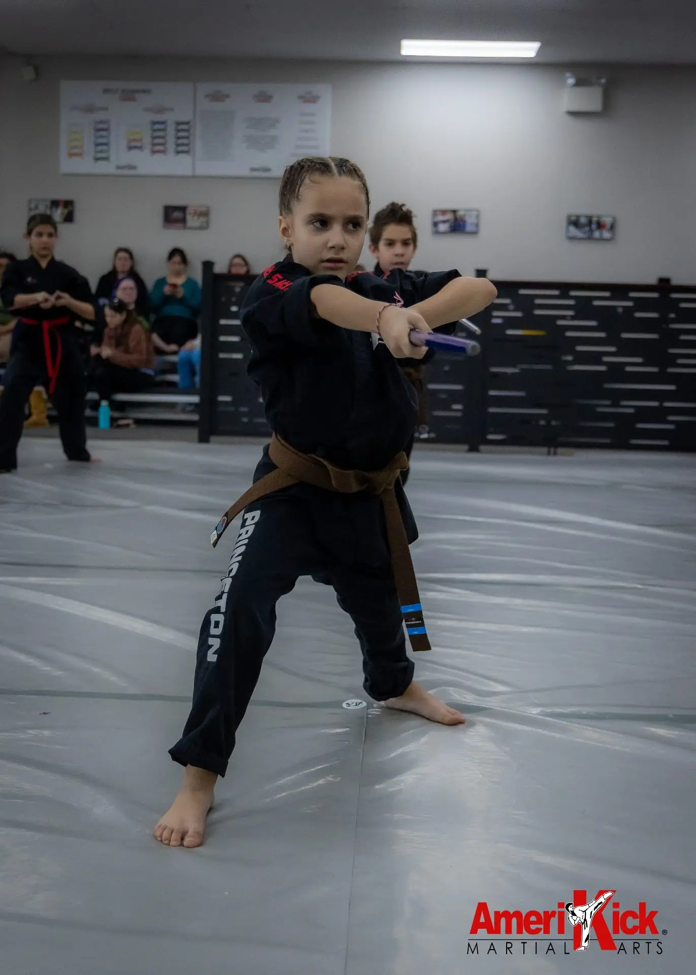 Kids Martial Arts brown belt student in focused stance with nunchucks