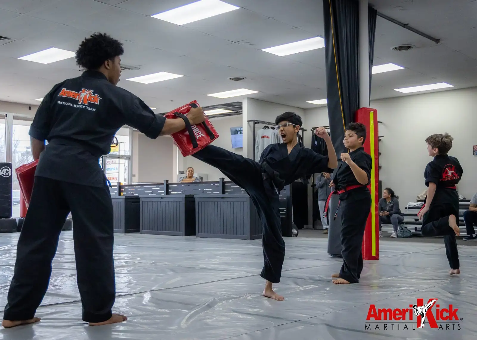 Kids Martial Arts student delivering a powerful side kick into a pad held by an instructor